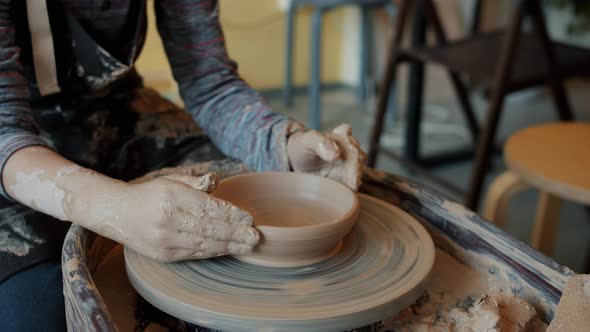 Slow Motion Close-up of Child's Dirty Hands Shaping Bowl From Clay on Pottery Wheel alt