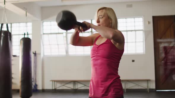 Fit caucasian woman working out with kettle bell at the gym alt