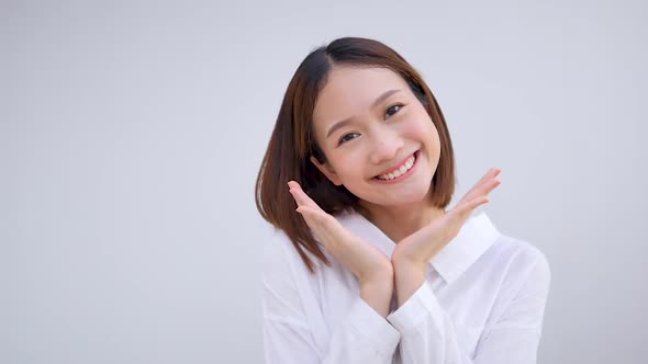 Cute Asian girl smiling happily stroking her face. Show positive emotions by wearing a white shirt.