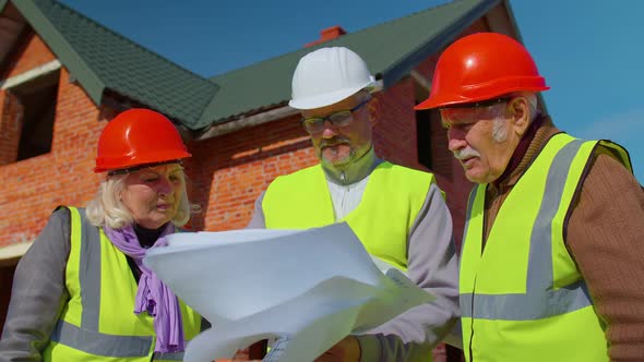 Realestate Agent Selling New House to Senior Grandmother Grandfather Showing Building Blueprints alt