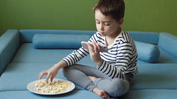 A Beautiful Boy Spends Time on the Internet Using a Smartphone alt
