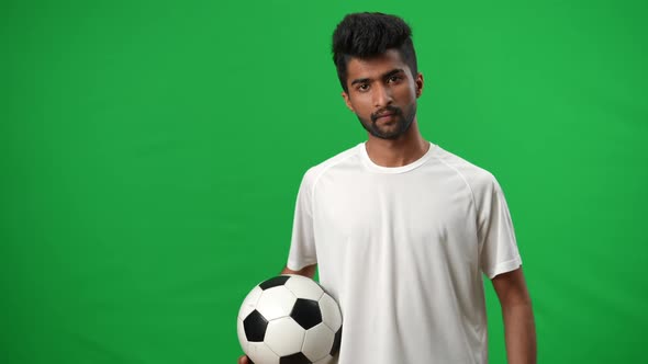 Portrait of Confident Positive Middle Eastern Footballer Posing on Green Screen with Soccer Ball alt