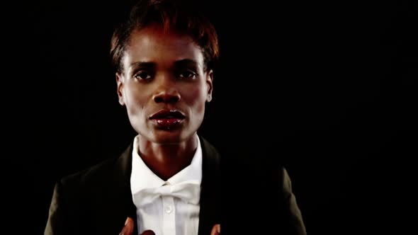 Androgynous man in suit posing against grey background alt