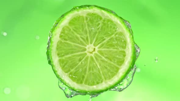 Super Slow Motion Detail Shot of Rotating Fresh Lime Slice and Splashing Water at 1000Fps alt
