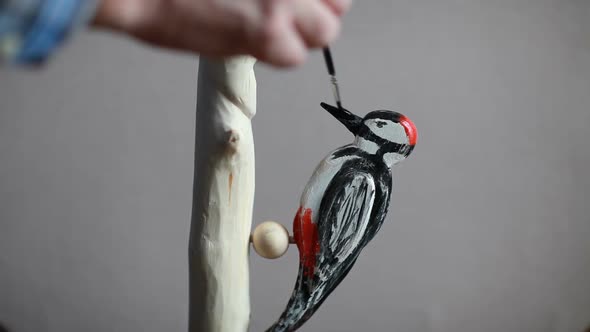 Artist paints a figurine of a red-headed woodpecker