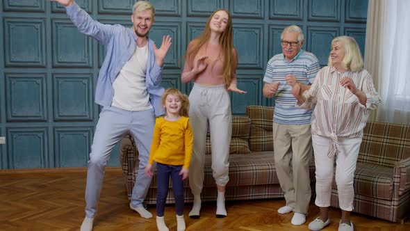 Family Members of Different Generations Having Fun Listening Music Dancing Crazy in Room at Home alt