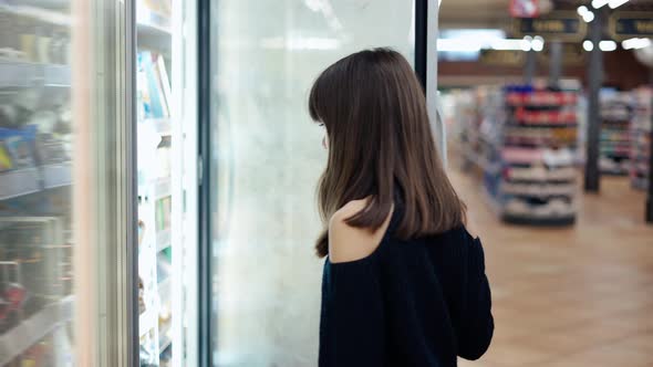 Independent Teenager in the Supermarket Opens Freezer Door and Take an Ice Cream alt