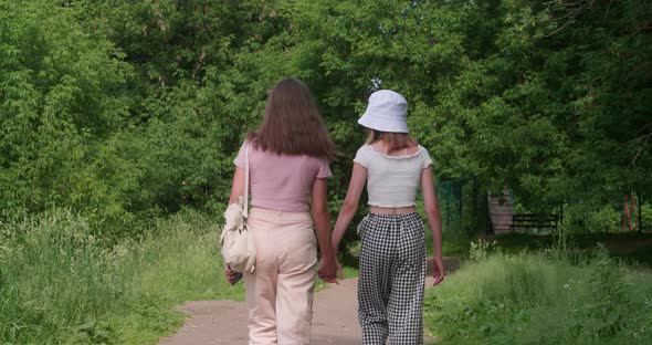 Young Girls Holding Hands and Looking Back at Camera Outdoors alt