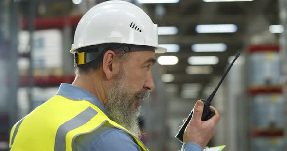Close Up of Aged Manager Using Walkietalkie in Warehouse alt