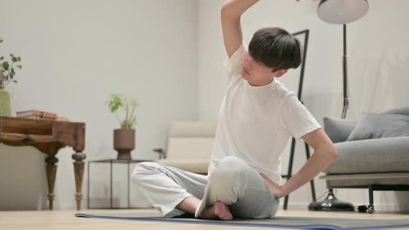 Asian Man Doing Stretches on Yoga Mat at Home alt