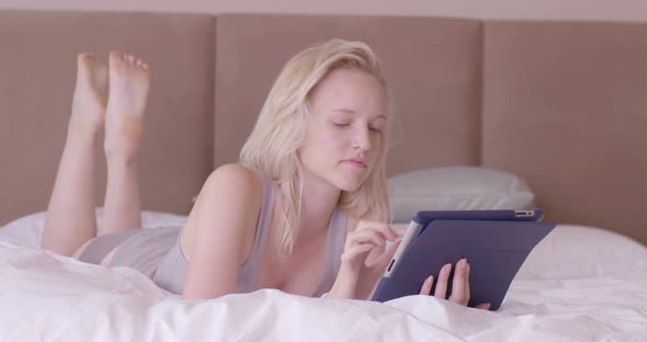 Woman lying on bed and using digital tablet