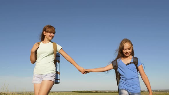 Girls, Women Travelers Go Holding Hands on a Background of Blue Sky. Close-up. Teamwork Tourists alt