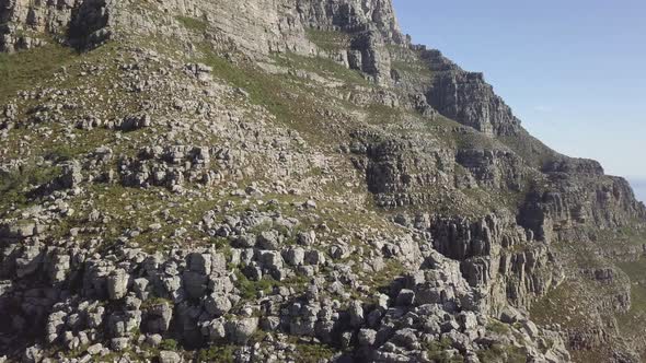 medium wide drone view of Table Mountain rock formation in late afternoon sun against blue sky with alt