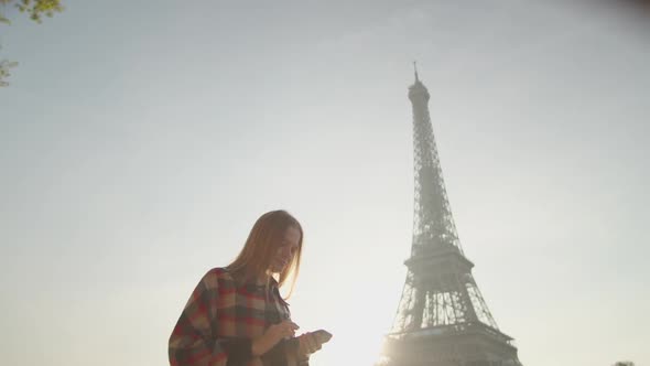 Young Woman Uses Smartphone App Walking Near Eiffel Tower in Paris France