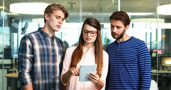 Executives discussing over digital tablet in office alt