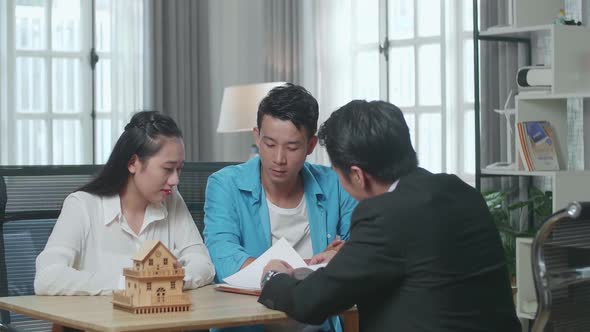Asian Couple Listens To A Real Estate Agent Explaining About House Purchase Contract At The Office alt