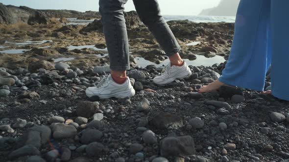 Two Beautiful Woman Walk Along the Volcanic Beach of Tenerife alt