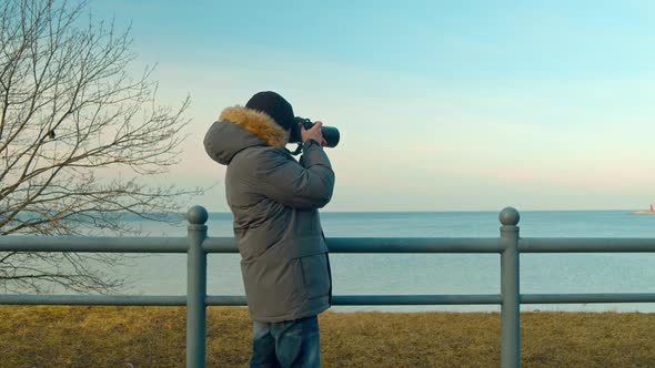 Male Photographer Takes Pictures of the Seascape on a Trip alt