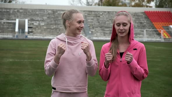 Young Fit Sporty Caucasian Pretty Twin Sisters Boxing Outdoors at Stadium Field alt
