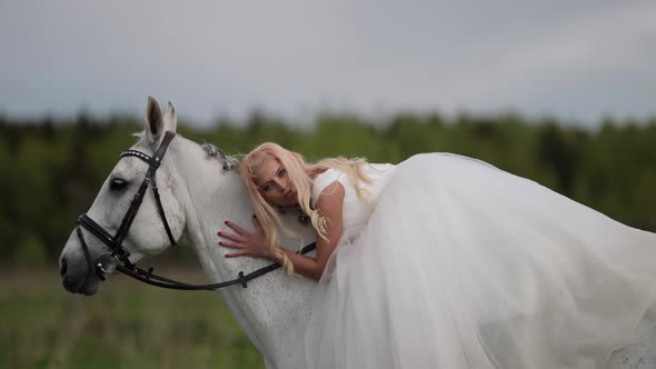 Happy Beautiful Bride is Riding White Horse at Summer Meadow Romantic Wedding Day alt