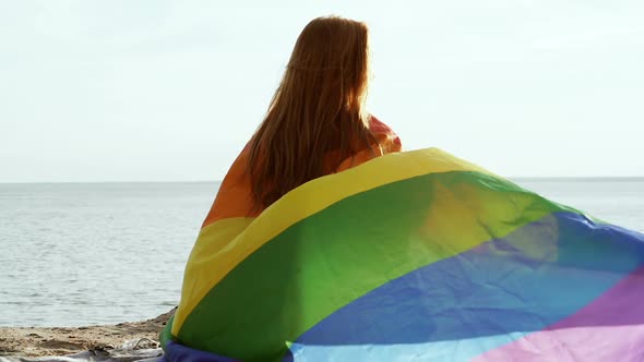 Woman sitting with rainbow flag.