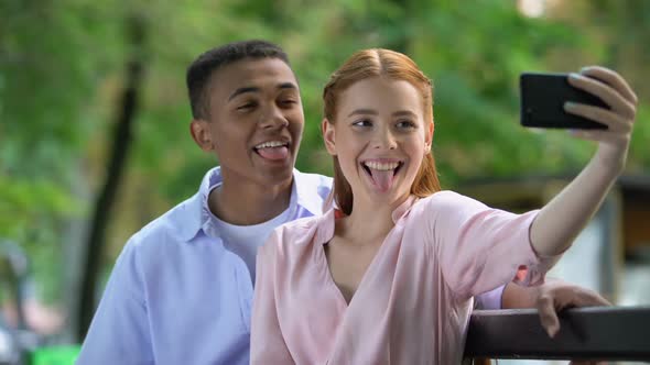 Smiling Teenage Couple Having Fun, Making Selfie Photos on Smartphone Camera alt