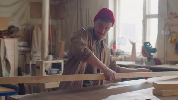 Woodworker Putting Plank on Workbench alt