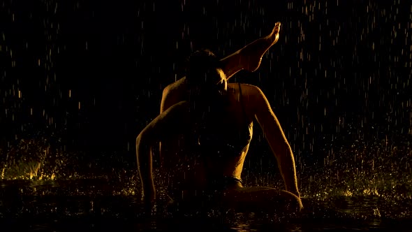 Exercise the Leg Behind the Head. Young Woman Practices Yoga Asanas in a Dark Studio in the Rain alt