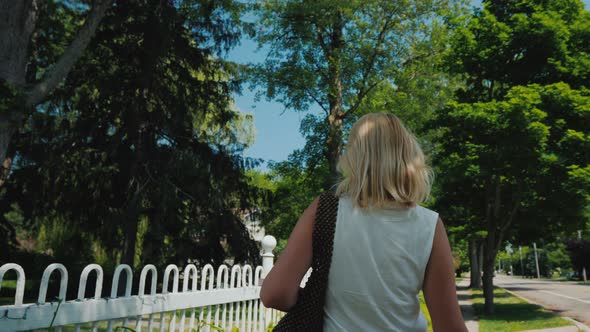 Young Woman Walking Down the Street in a Typical American Suburb, Rear View alt