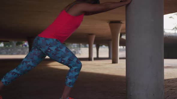 Caucasian woman stretching under a bridge alt