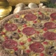 A cooked sesame crust pizza with salami, mushroom, tomato and mozzarella on a wooden plate - VideoHive Item for Sale