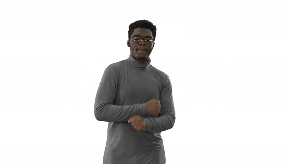 Young African American Man in Grey Clothes and Glasses Grooving While Walking on White Background. alt