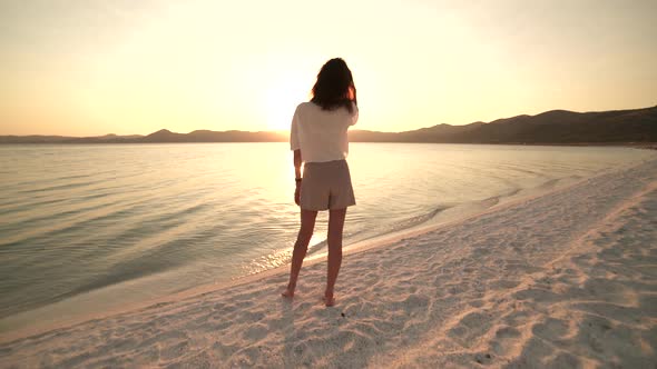 Female Model Walking on the White Sandy Beach of the Clear Tropical Turquoise Sea at Sunset alt