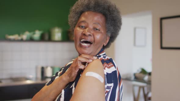 Happy senior african american senior woman showing plaster on arm after covid vaccination alt