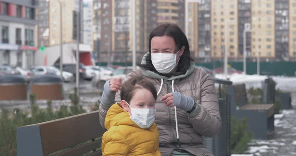 A Mother Puts Protective Mask on Herself and on Her Little Son