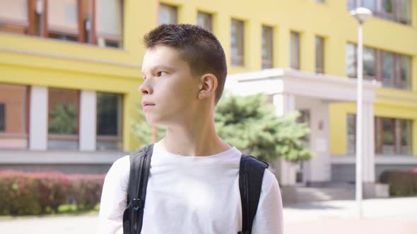 A Caucasian Teenage Boy Looks Around   a School in the Background