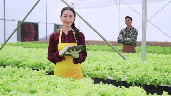 asian male and female farmer checking quality of greenhouse hydroponic farm