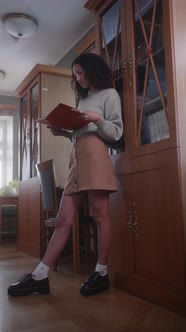 Education Stock Footage 4 K Ultra Hd Clips   A Woman Reading A Book While Leaning On A Bookshelf alt