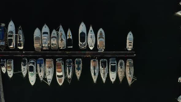 Birds Eye View of Sailboats in Harbour with Black Water Background, Aerial Top Down View alt