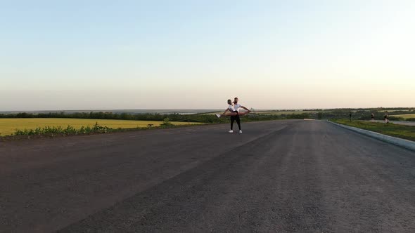 Sunrise Outdoor Woman Is Doing a Split While a Man Is Holding Her Film Grain alt