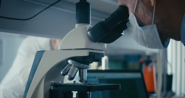 Scientist Studying Sample in Microscope alt