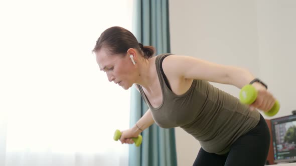 A Woman Performs an Exercise Spreading Her Arms to the Sides with Dumbbells While Standing in an alt