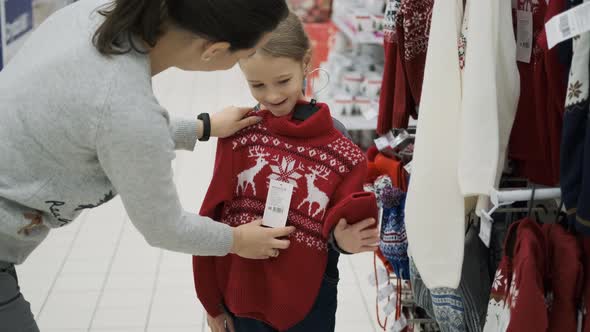 Mother Buying Xmas Sweater for Little Daughter alt