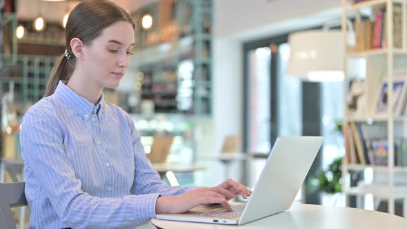 Laptop Use By Young Businesswoman Looking at Camera in Cafe alt
