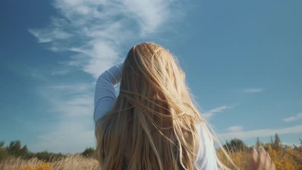 A Young Girl in a Beautiful Dress Will Scatter Her Hair in a Strong Wind alt