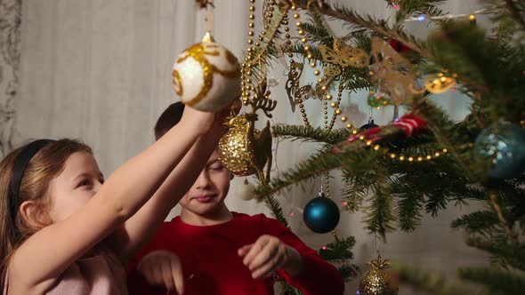 Decorating the Christmas Tree Hanging Ornaments a Girl and Boy Clings a Toy alt