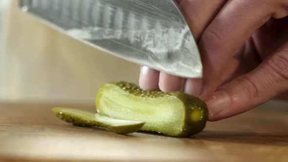 Professional cuts canned cucumber with knife slices for making burger alt