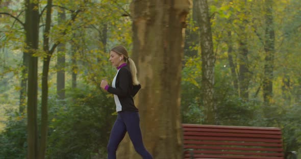 Fitness Girl Runs in the Morning Light in the City Park alt