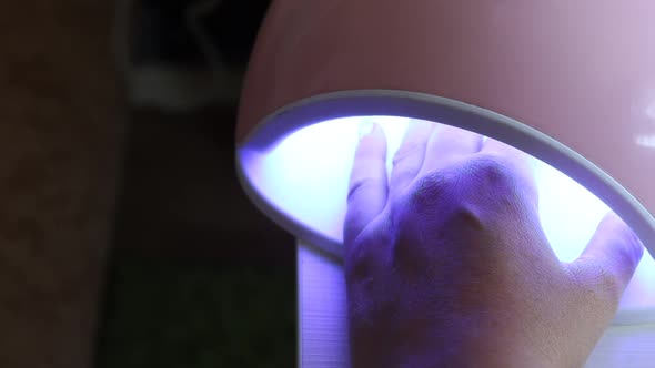 A Woman Dries Her Nails In An Ultraviolet Lamp. She Gives Herself A Manicure.