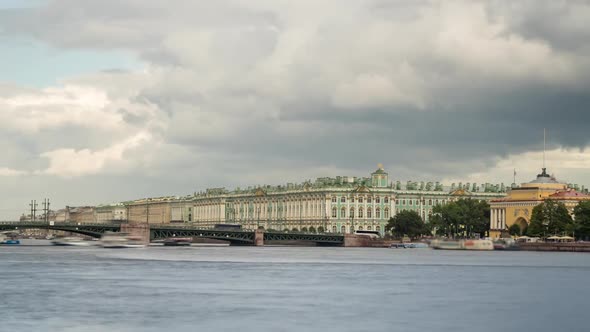 Dramatic cloudy sky over the Bridge and Winter Palace with boats on the Neva River.